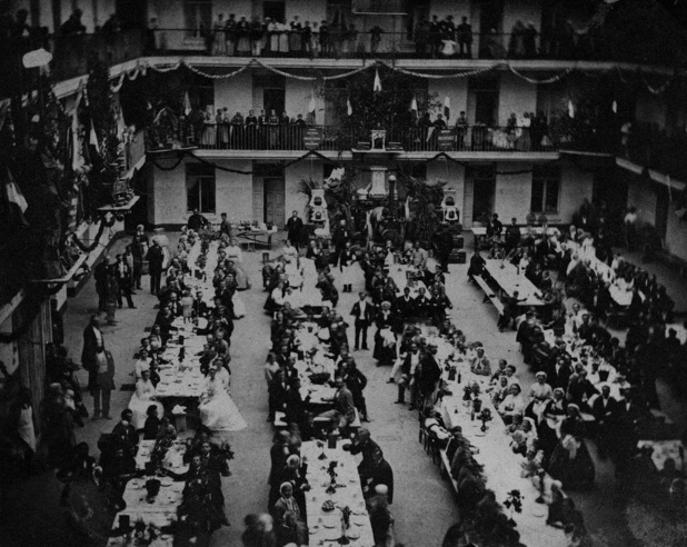 Banquet de la Fête du travail dans la cour du pavillon central, le 6 juin 1870. Le calendrier familistérien est rythmé par deux fêtes laïques inédites : la Fête de l’enfance se tient en septembre depuis 1863, et la Fête du travail créée en 1867 se célèbre le premier dimanche de mai. La Fête du travail familistérienne anticipe de deux décennies le Premier mai de la revendication de la journée de huit heures - DR : Familistère Banquet de la Fête du travail dans la cour du pavillon central, le 6 juin 1870. Le calendrier familistérien est rythmé par deux fêtes laïques inédites : la Fête de l’enfance se tient en septembre depuis 1863, et la Fête du travail créée en 1867 se célèbre le premier dimanche de mai. La Fête du travail familistérienne anticipe de deux décennies le Premier mai de la revendication de la journée de huit heures - DR : Familistère