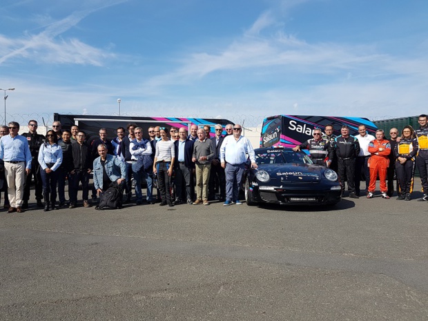 Michel Salaün et Jacques Laffite posent à côté de la Porsche 997 GT, des pilotes et des représentants des partenaires tour-opérateurs et voyagistes venus découvrir le circuit du Mans - Photo CE