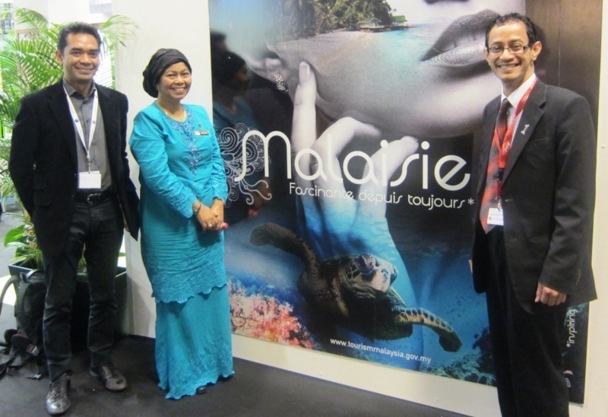 L'équipe de l'office du tourisme de Malaisie devant l'affiche de sa campagne de communication : " La Malaisie - Fascinante depuis toujours". DR