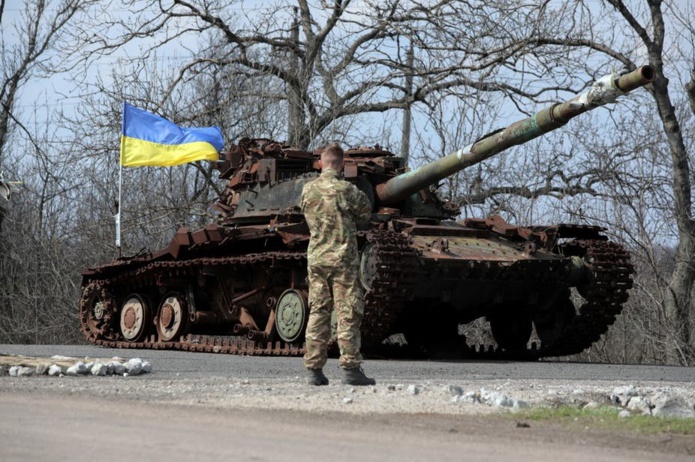 Un militaire ukrainien se tient devant un char détruit en 2014 par les séparatistes soutenus par la Russie, sur la ligne de front près de la petite ville de Pisky, dans la région de Donetsk, le 21 avril 2021. Aleksey Filippov/AFP