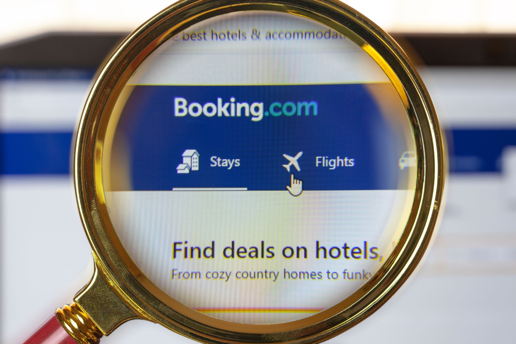 un moteur de recherche pour réserver des hôtels dans le monde "booking.com", gros plan sous une loupe grossissante © evgenii - stock.adobe.com