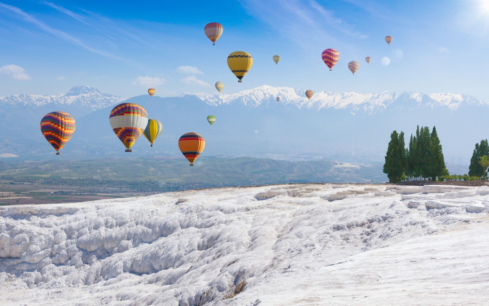 Collage avec des ballons à air chaud volant au-dessus de Pamukkale blanc enneigé en Turquie © IgorZh - stock.adobe.com
