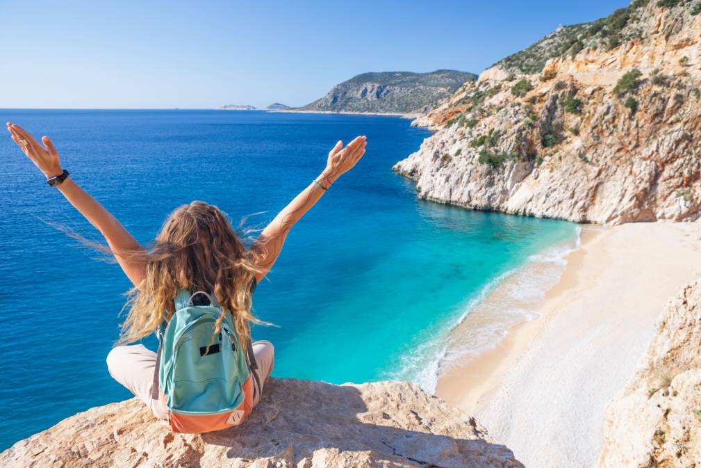 Mujer joven con mochila mirando la playa de Kaputas, costa de Licia.  Paseo de verano por el Camino Licio durante unas vacaciones familiares en el Mar Mediterráneo, Kas, región de Antalya, Turquía.  © Tropical Studio - stock.adobe.com