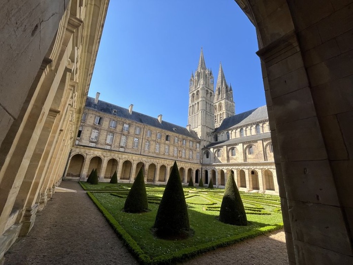 Le cloître de l'Abbaye aux hommes et au fond, le clocher de l'église abbatiale (© PB)