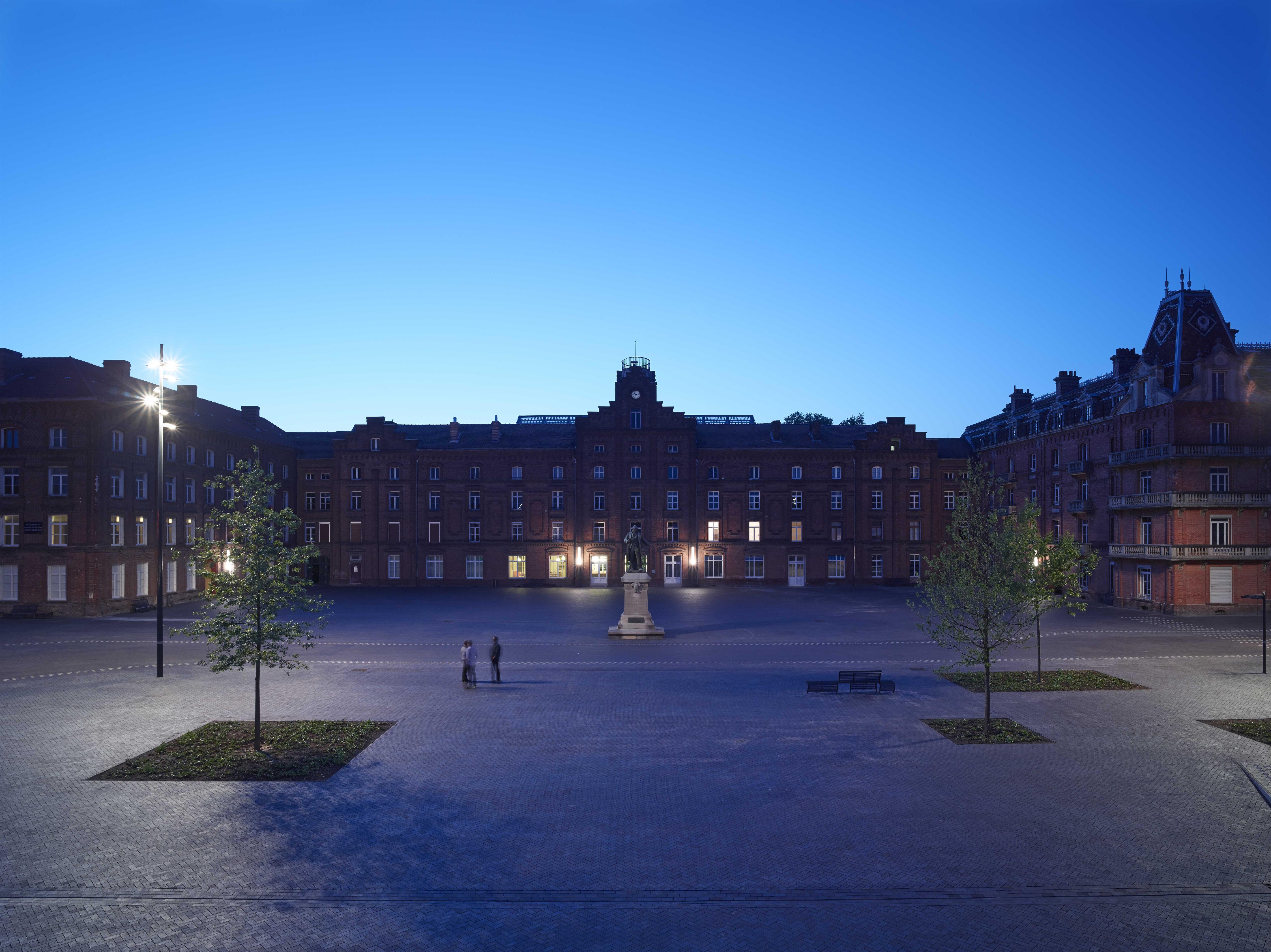 La place du Palais social. 3 grands pavillons d’habitation collective construits en U totalisent 500 appartements où vivent 1 800 personnes. Les « familistériens » ont à disposition des magasins, une école, une crèche, une buanderie, un théâtre, un kiosque à musique et même une piscine chauffée. Photo Stéphane Chalmeau. Fam. de Guise.