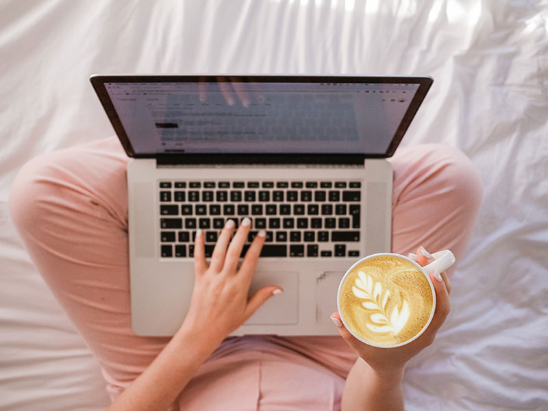 une personne qui utilise un MacBook Pro et qui tient un cappuccino © Sincerely Media
