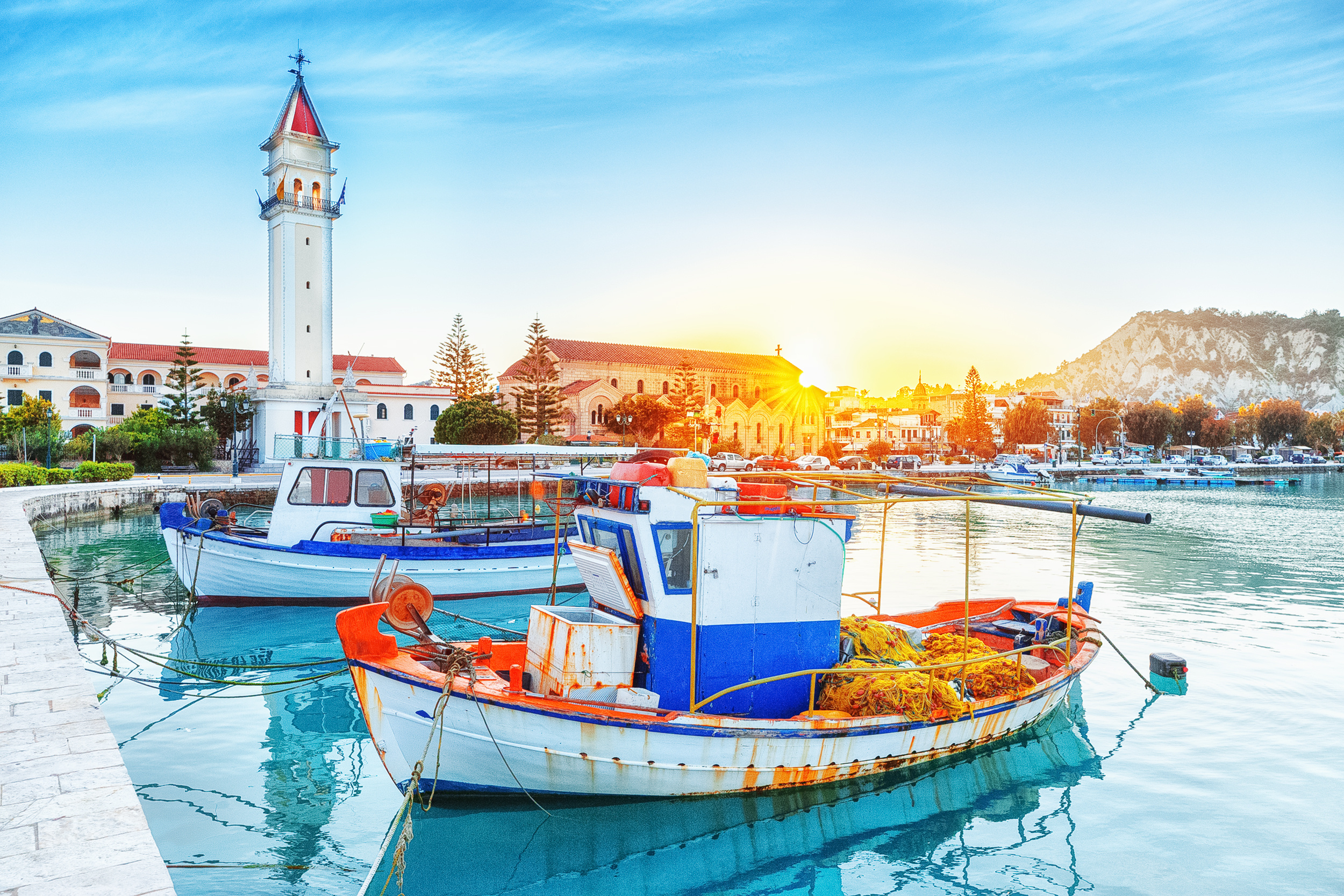 Zante - île de Zakinthos, vieux port avec bateaux amarrés et point de repère de la tour de l'église. Paysage de coucher de soleil majestueux, soleil brillant visible. © Feel good studio - stock.adobe.com