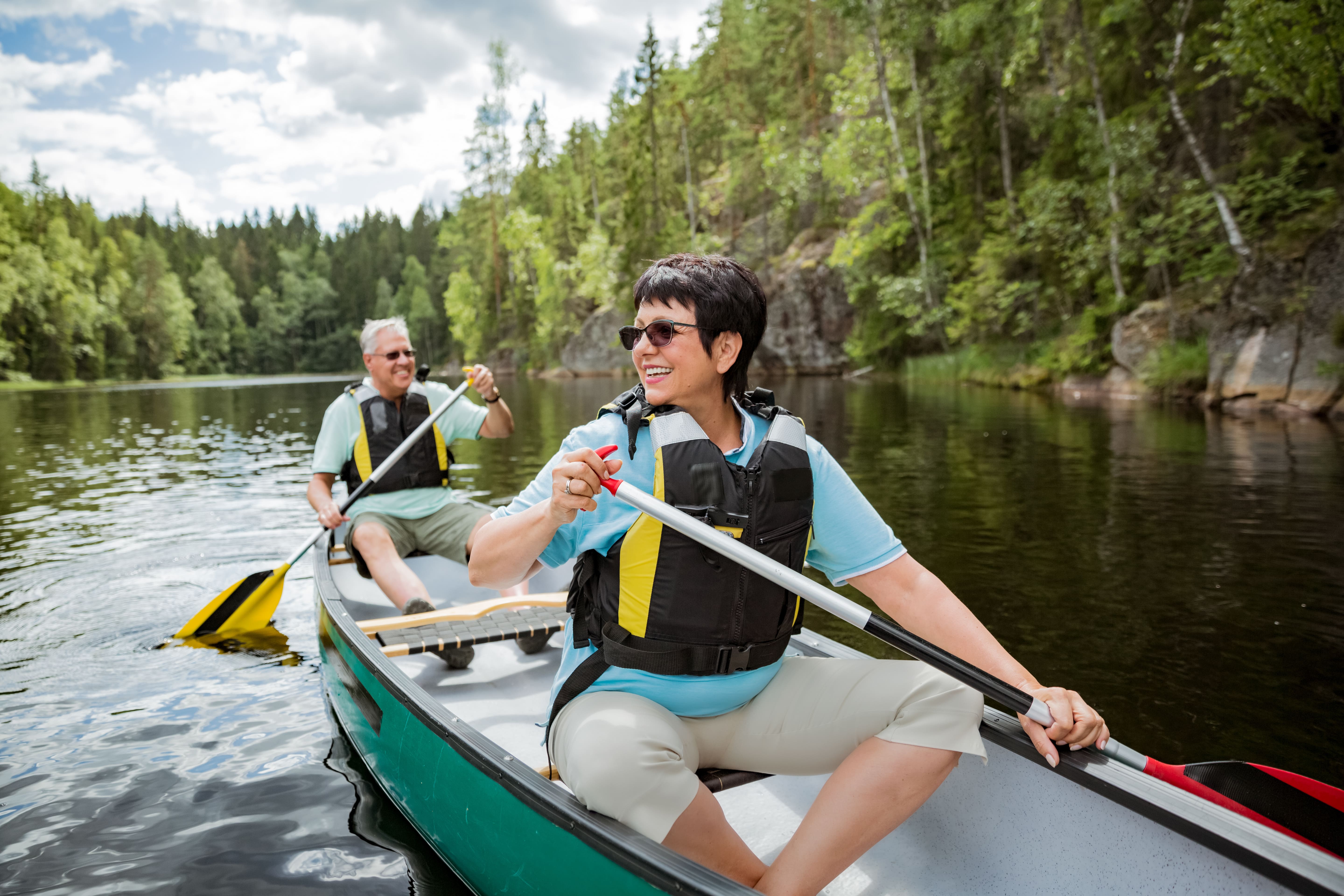 Heureux couple mature en gilets de sauvetage canoë-kayak dans le lac de la forêt. Journée d'été ensoleillée. Touristes voyageant en Finlande, ayant l'aventure. © Suzi Media - stock.adobe.com