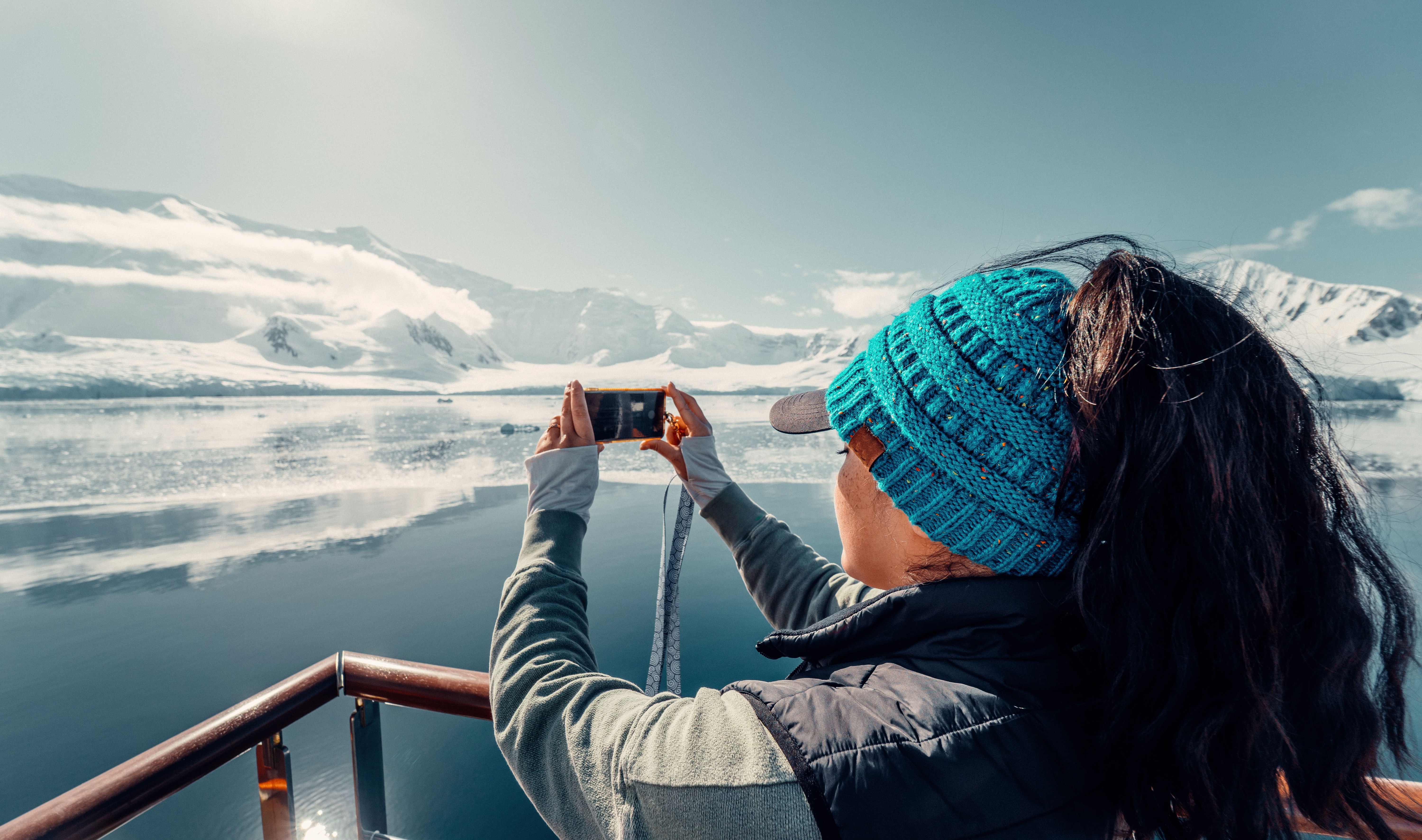 Une touriste sur un bateau de croisière de luxe en Antarctique regarde le paysage arctique époustouflant, tout en prenant une photo avec son téléphone, photo de paysage. ©  David - stock.adobe.com