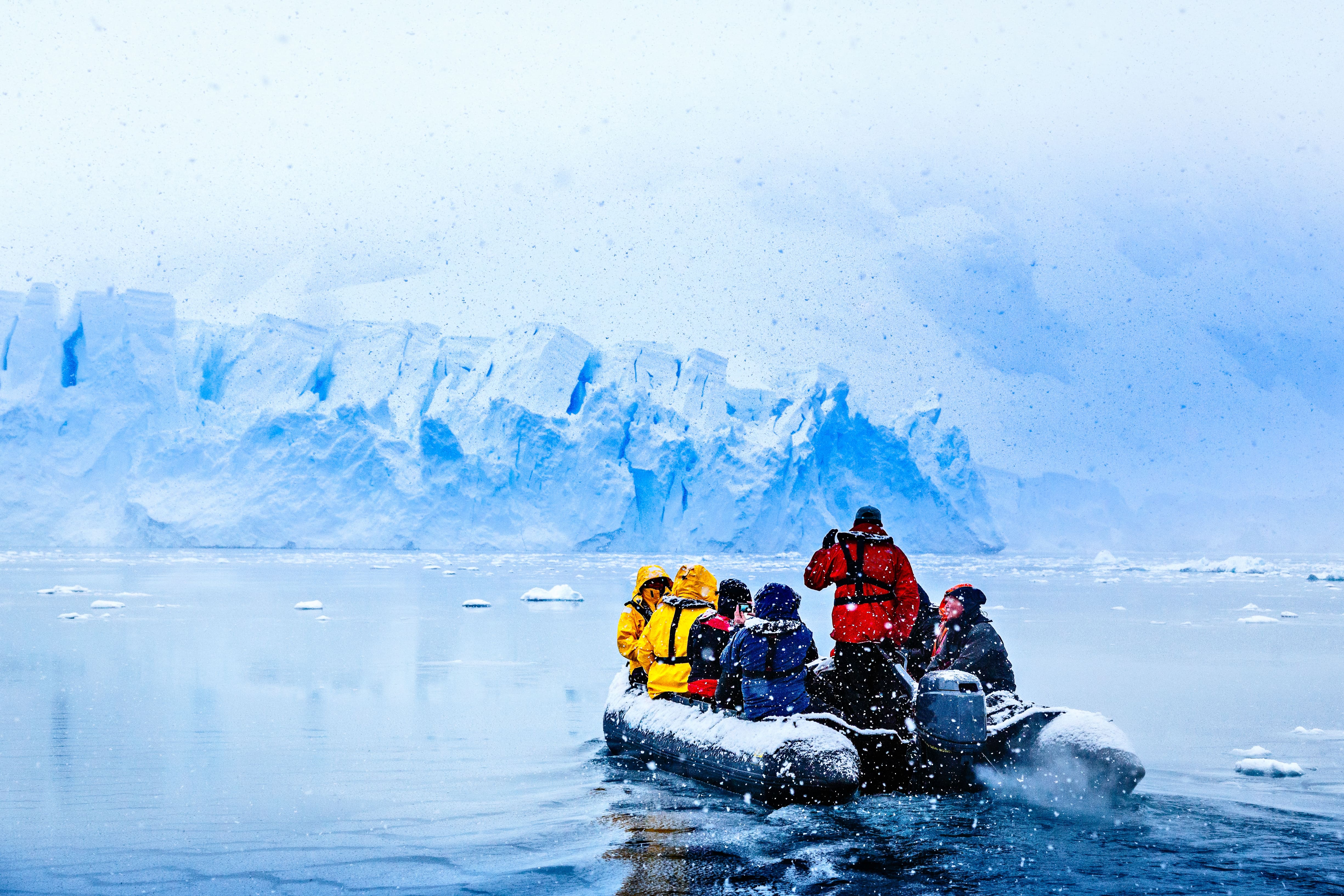 Chute de neige sur le bateau avec des touristes gelés conduisant vers l'énorme mur de glacier bleu en arrière-plan, près d'Almirante Brown, péninsule Antarctique © vadim.nefedov - stock.adobe.com