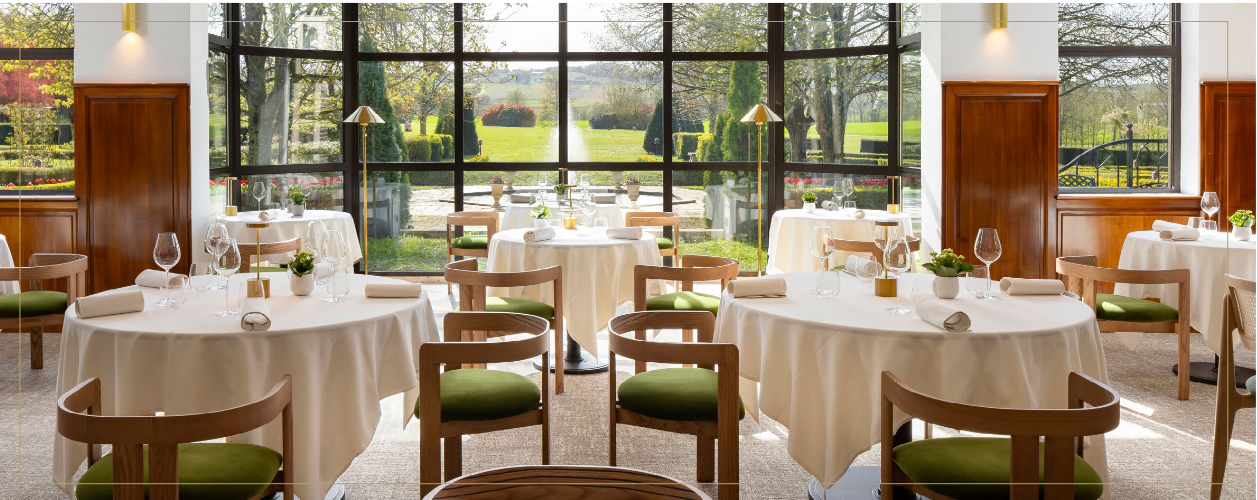Dans la salle du restaurant, le large bow-window fait face aux pièces d’eau du parc (©Hostellerie Briqueterie &Spa • Champagne)