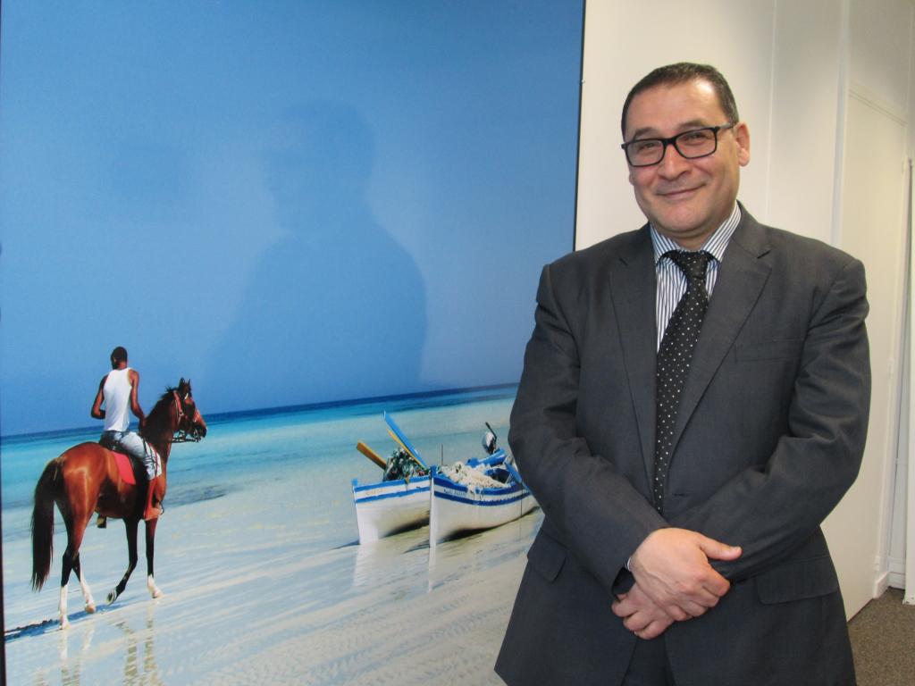 Abdellatif Hamam, directeur général de l’ONTT, devant une photo de Djerba dans les nouveaux bureaux de l'OT, avenue de l'Opéra à Paris - DR : M.S.