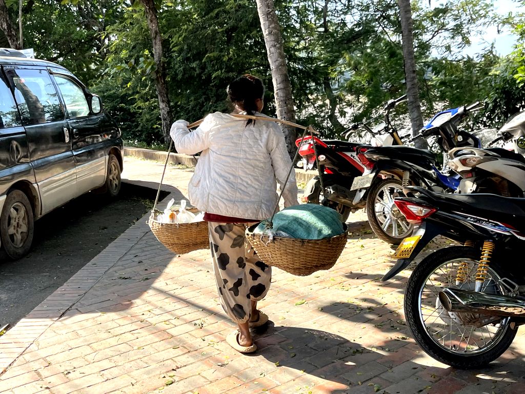 A Luang Prabang, les porteuses traditionnelles voisinent avec les voitures et les motos - Photo : PB