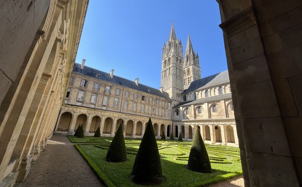 Le cloître de l'Abbaye aux hommes et au fond, le clocher de l'église abbatiale (© PB)